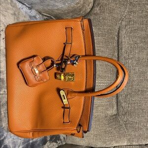 Elegant tan Leather Handbag with a miniature bag charm that matches.
